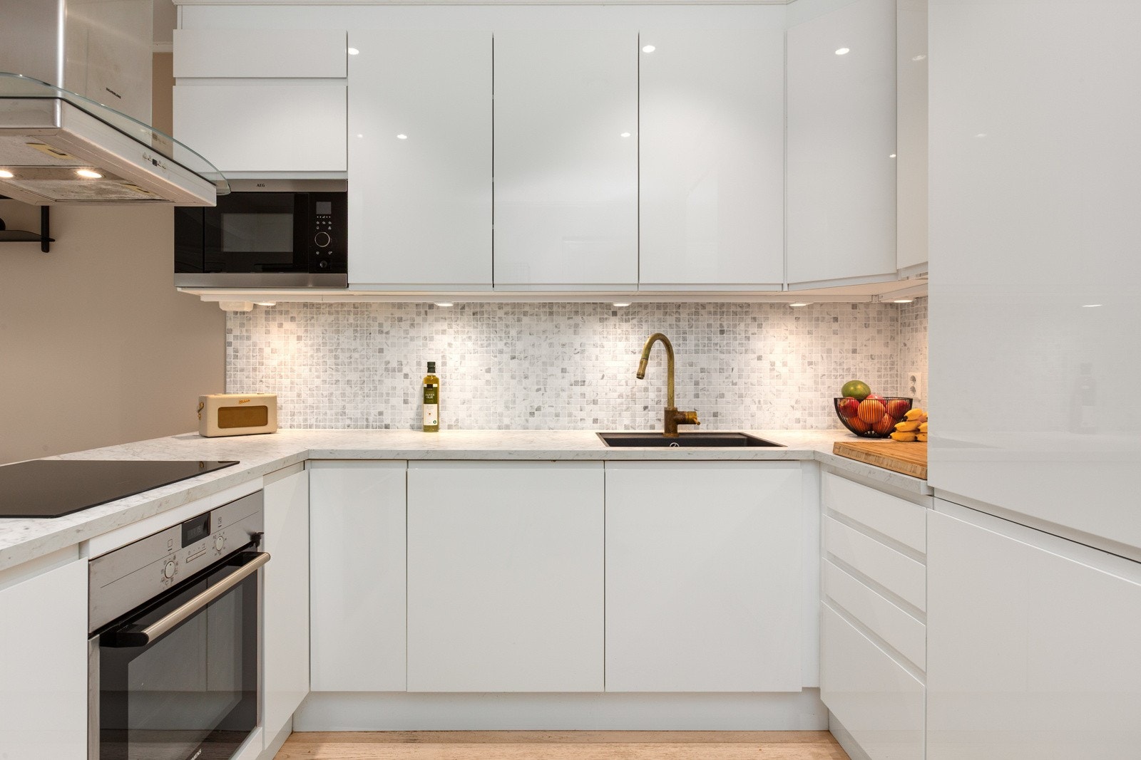 Kjøkkenet har en tidløs utførelse med høyglans hvit innredning, marmorimitert benkeplate og mosaikkfliser i marmor mellom over- og underskap. Det er innebygd mikrobølgeovn, komfyr, platetopp og oppvaskmaskin. Alle hvitevarer medfølger. Galleribilde