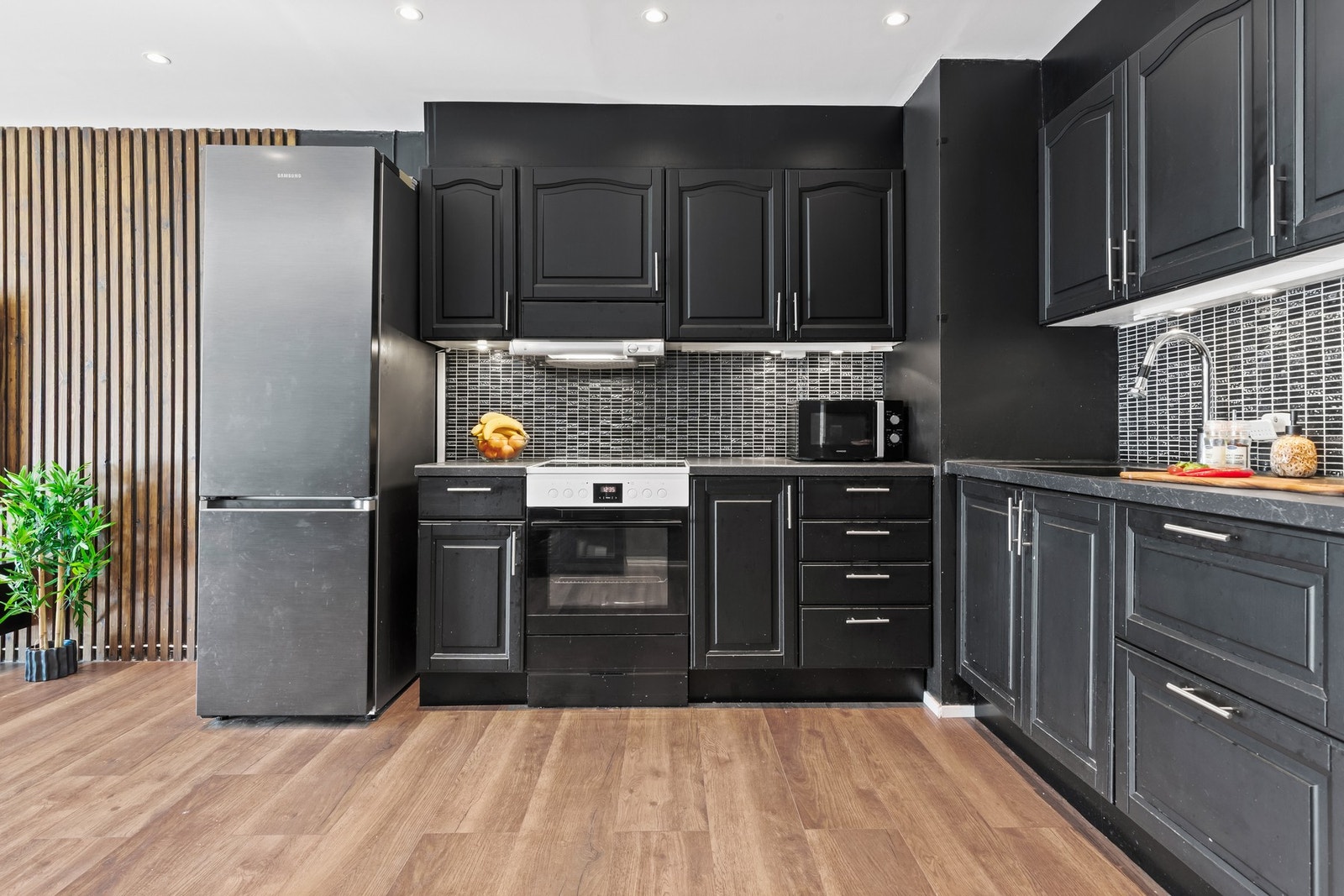 De svarte frontene gir et moderne uttrykk, mens benkeplaten gir god plass til matlaging. Fliser over benk gir et tidløst preg, og her er det nisjer for hvitevarer. Galleribilde