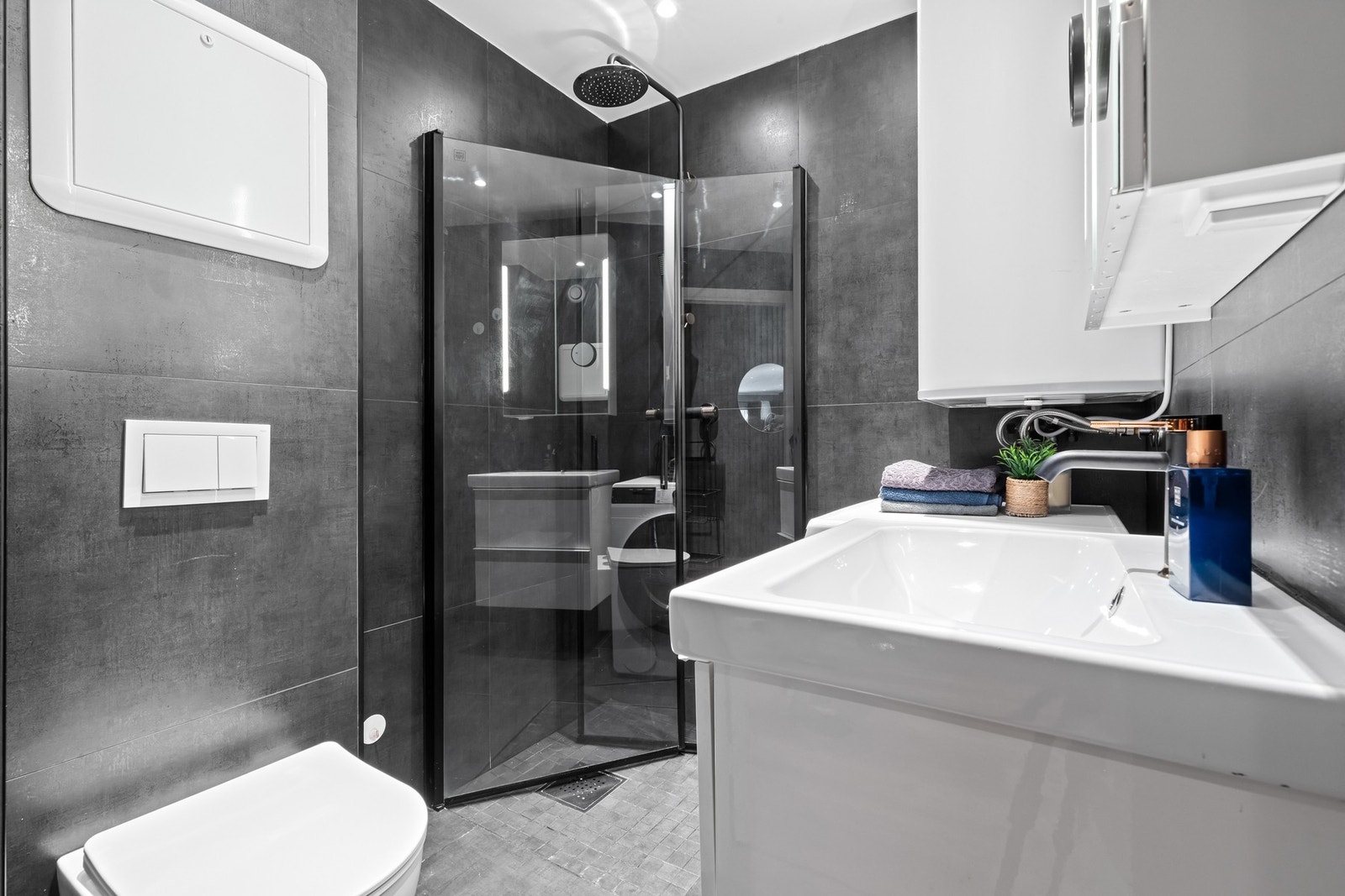 Badet ble totalrenovert i 2023 og er i dag moderne. e mørke flisene skaper en eksklusiv følelse, mens den lyse innredningen gir en fin kontrast. Galleribilde