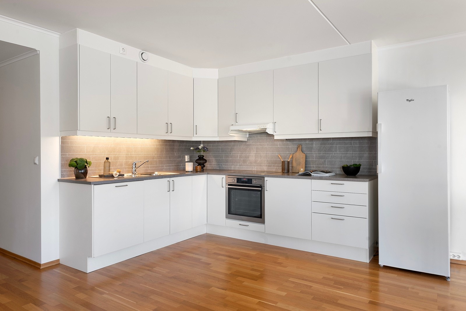 På kjøkkenet har du lys innredning med slette fronter, og hvitevarer som oppvaskmaskin, stekeovn og platetopp integrert Galleribilde