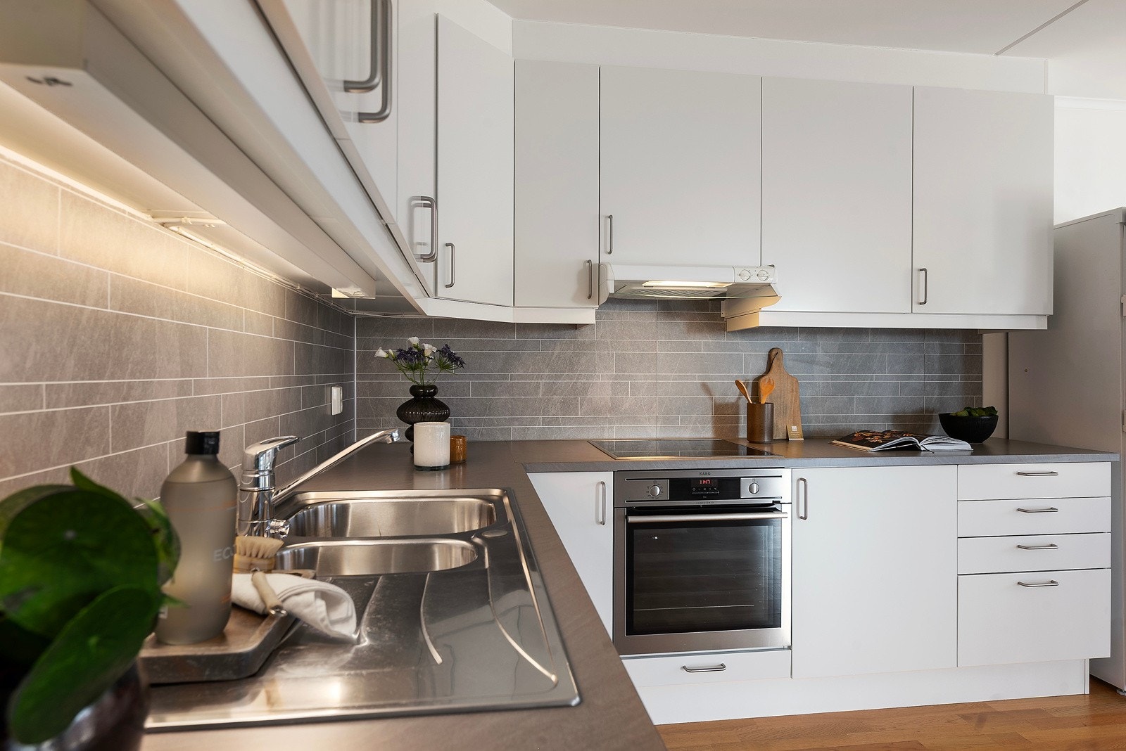 Med kjøkkenplater mellom overskap og kjøkkenbenk, får kjøkkenet et moderne utrrykk samtidig som det er enkelt å holde rent Galleribilde