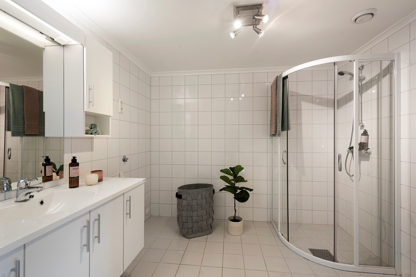 Badet er stort, helfliset og romslig, med dusjhjørne, servant med skuffer, toalett og opplegg for både vaskemaskin og tørketrommel Galleribilde