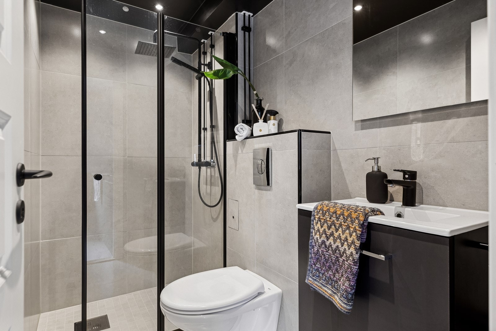 Lekkert og flislagt baderom med vegghengt toalett, dusjhjørne og servant. Varmekabler i gulv og regndusj. Galleribilde