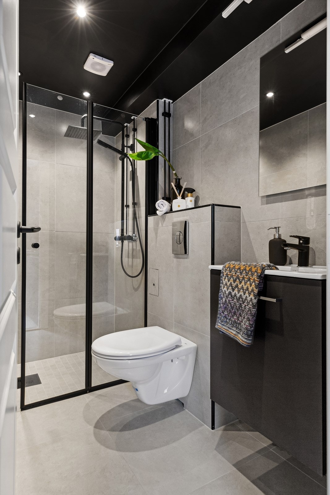 Baderommet har gulvvarme og spotbelysning. Moderne detaljer i sort og avtrekk over dusjsone. Galleribilde