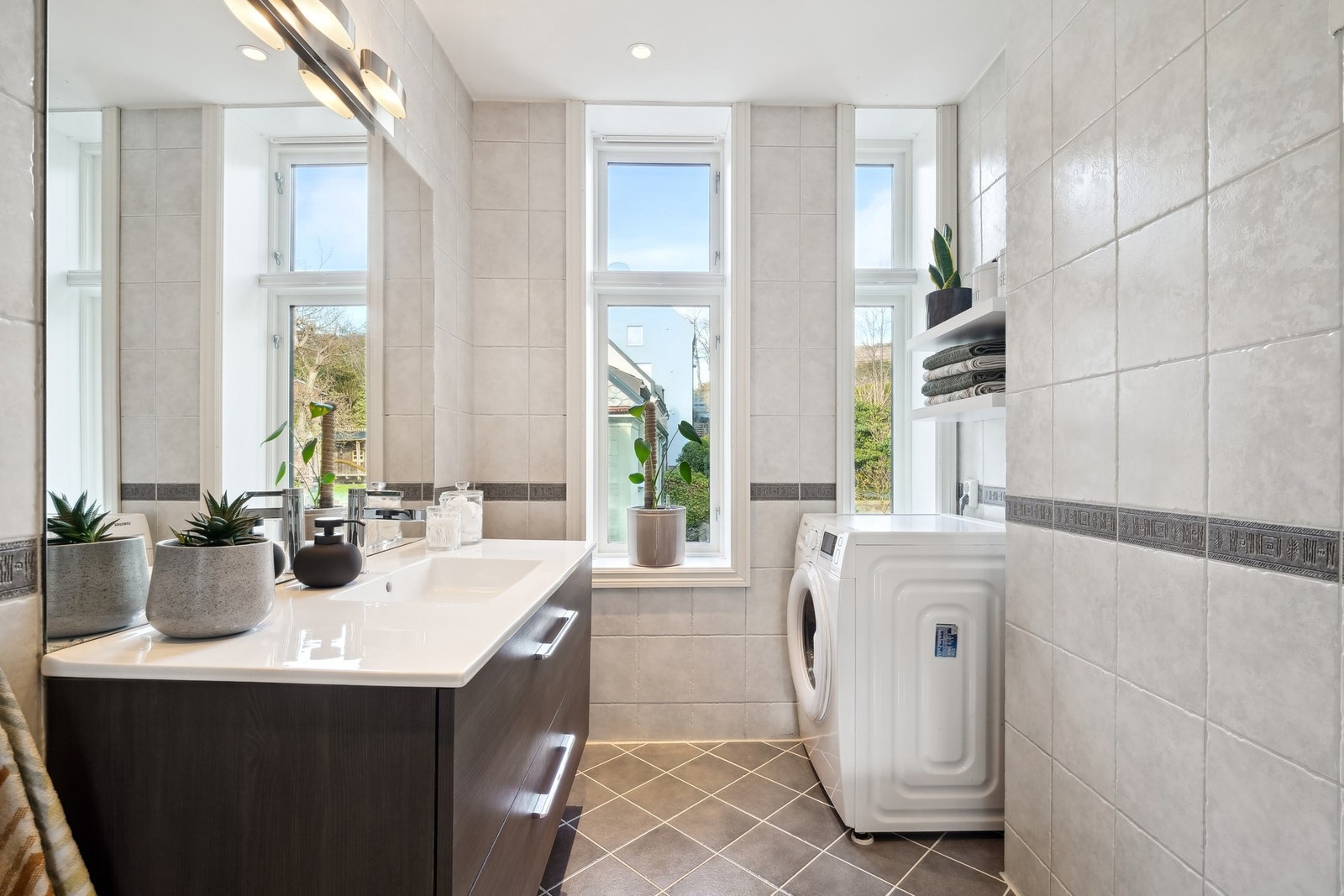 Lyst og pent flislagt bad med opplegg for vaskemaskin Galleribilde