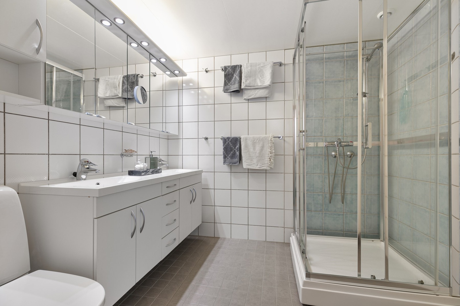 Bad fra byggeår, der sluk er skiftet i 2020 og det er lagt flis på flis på gulvet også i 2020. Gulv og vegger er flislagt, mens tak består av folierte plater. Galleribilde