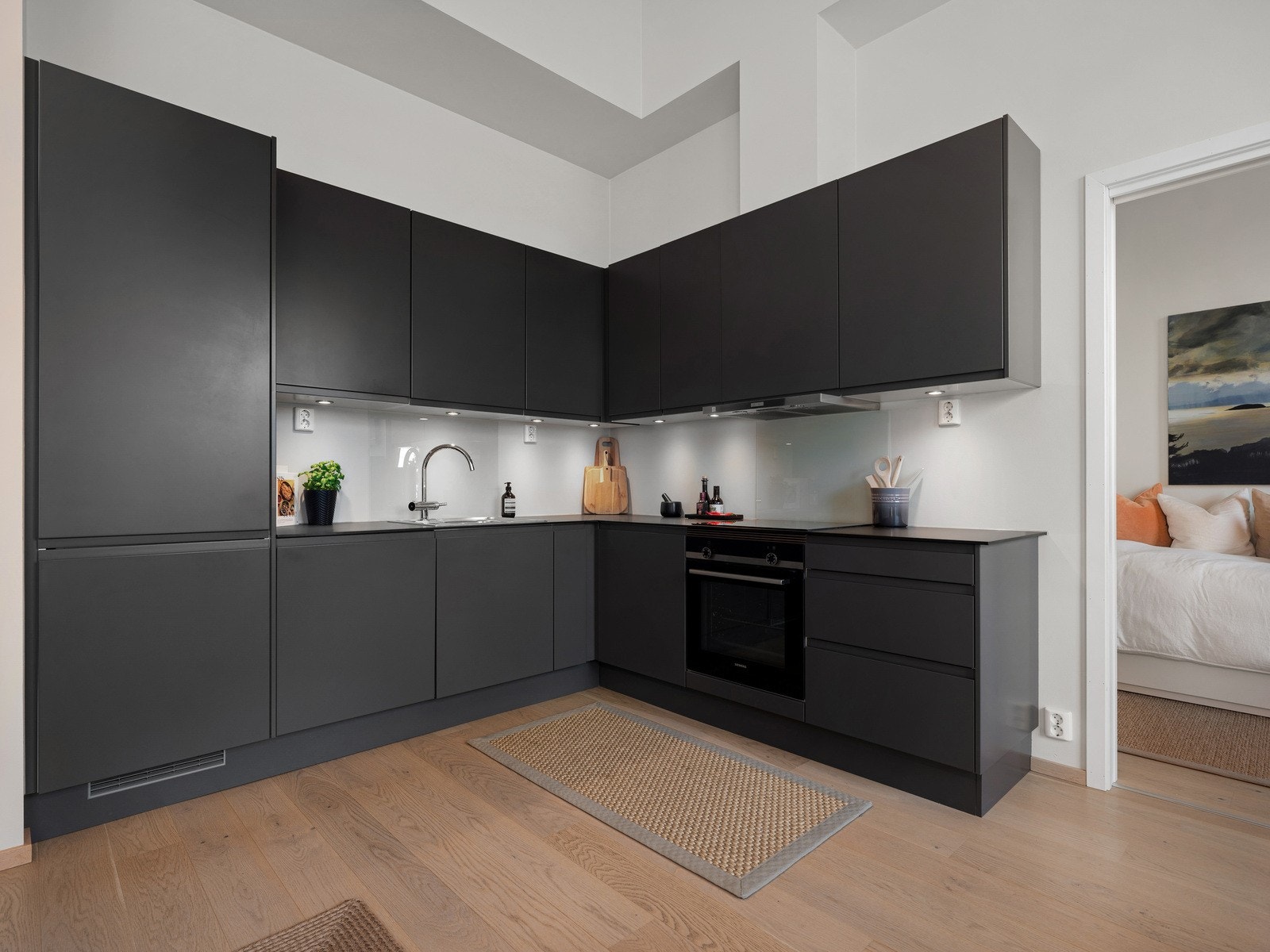 Kjøkkeninnredningen fra SIGDAL består av glatte fronter og en elegant laminat benkeplate som inneholder en nedfelt kum i rustfritt stål. Galleribilde