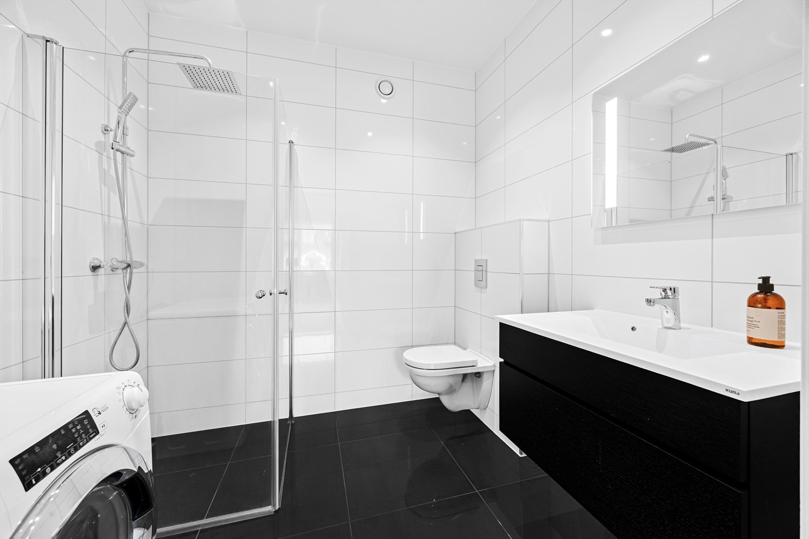 Pent flislagt baderom med servant, wc, dusj og opplegg for vaskemaskin. Galleribilde