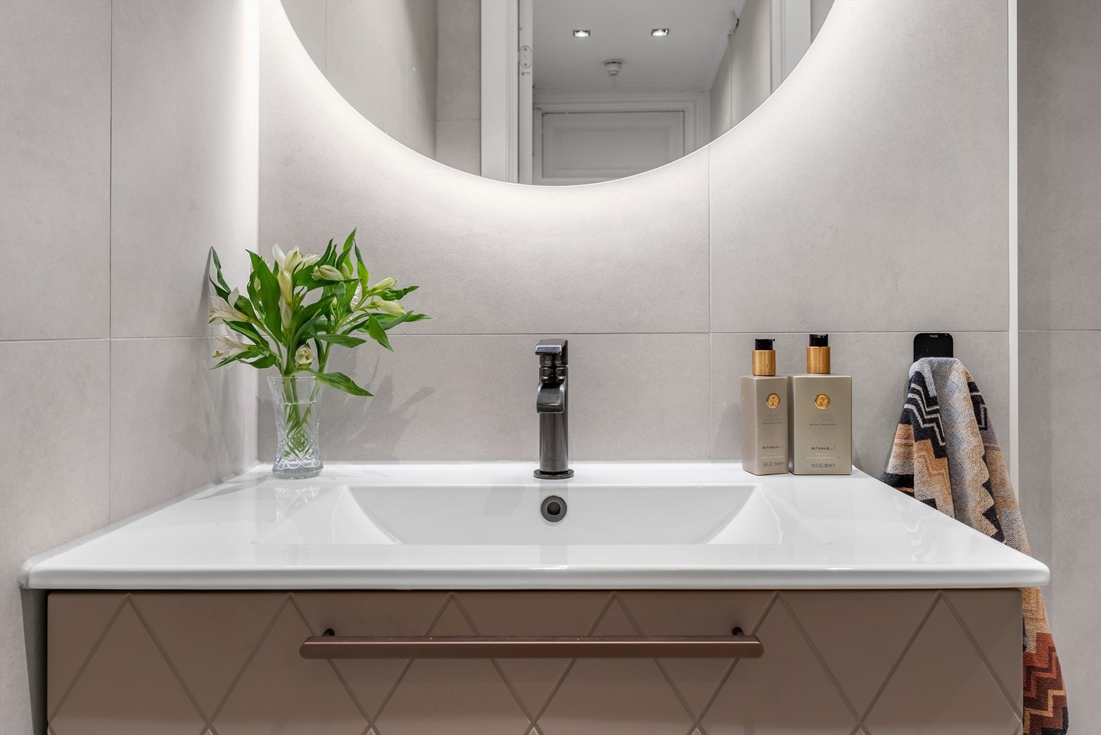 Stilig innredning på badet. Speil med lys og servant med skuffer. Galleribilde