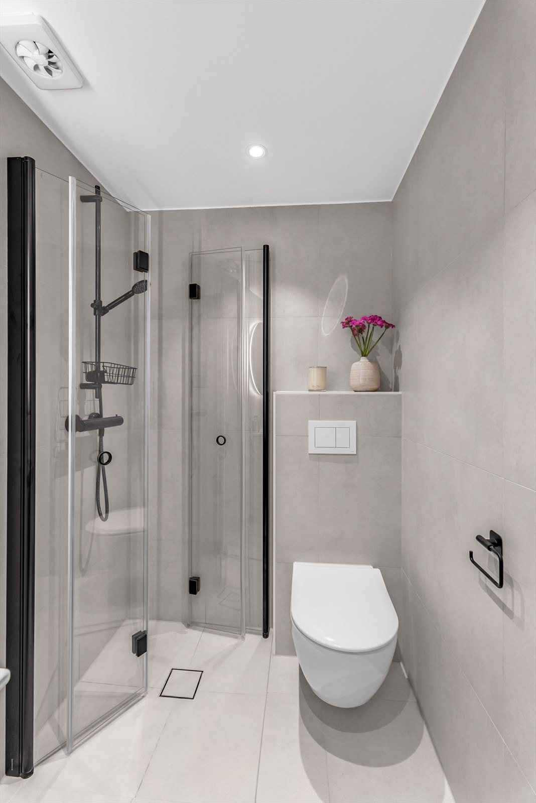 Dusjhjørne med foldedører i glass og vegghengt wc med innebygget sisterne. Galleribilde