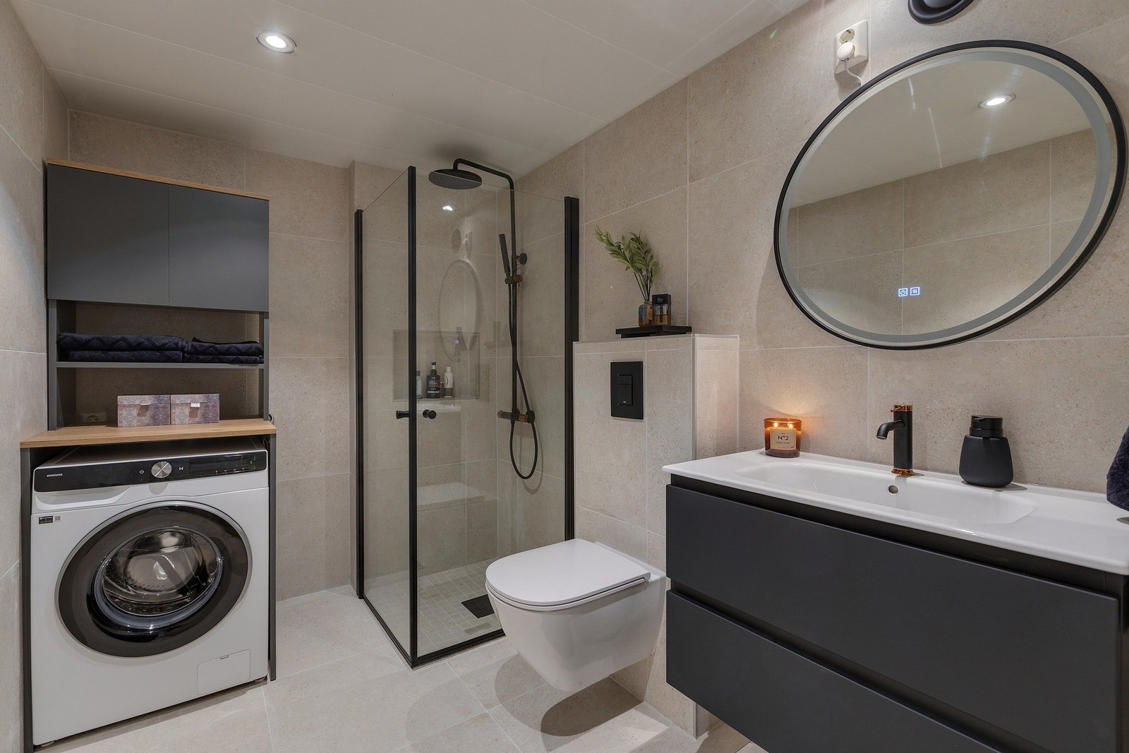 Badet har innredning med nedfelt servant, veggmontert toalett, dusjvegger/hjørne og opplegg for vaskemaskin Galleribilde