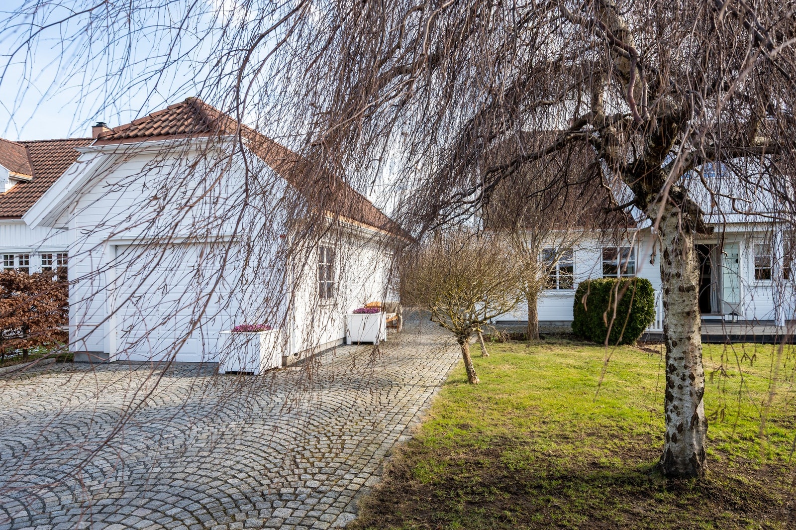Eiendommen har en pent opparbeidet tomt med gressplen, beplantning, brosteinsbelagt adkomst fra gaten og flere biloppstillingsplasser. Galleribilde