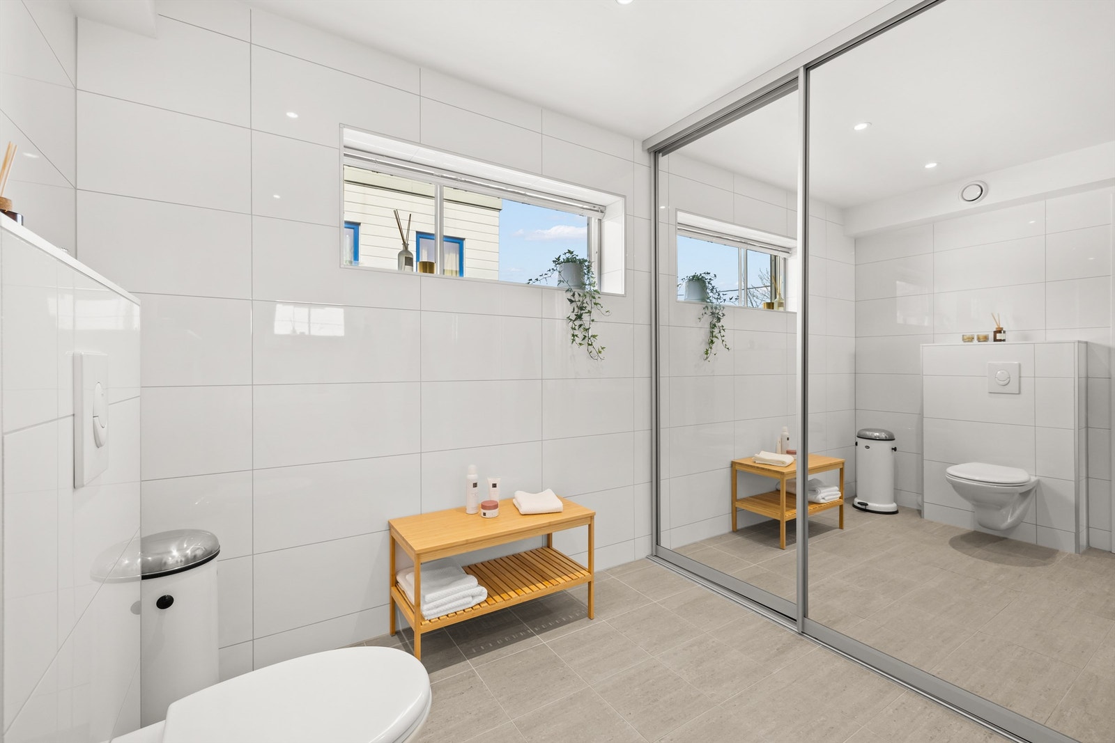 Hovedbad med opplegg for vaskemaskin og tørketrommel bak skyvedørene. Galleribilde