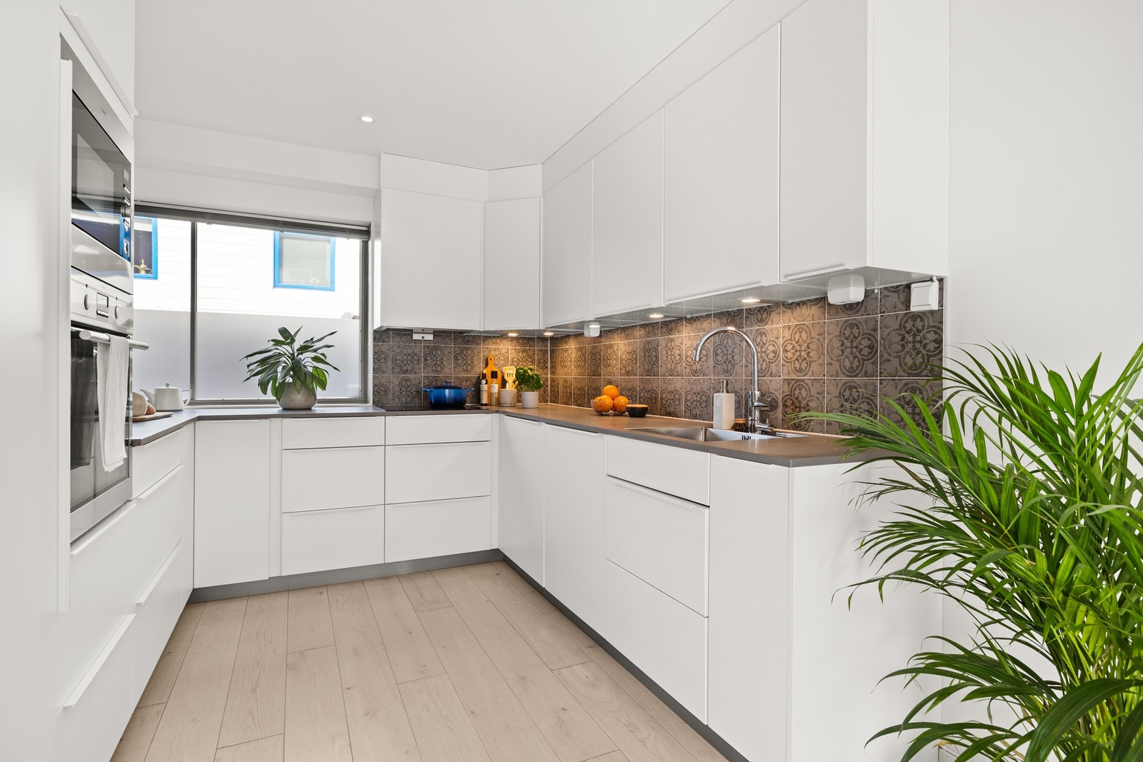 Kjøkkeninnredning fra Kvik med glatte hvite fronter og grå benkeplate av laminat. Galleribilde