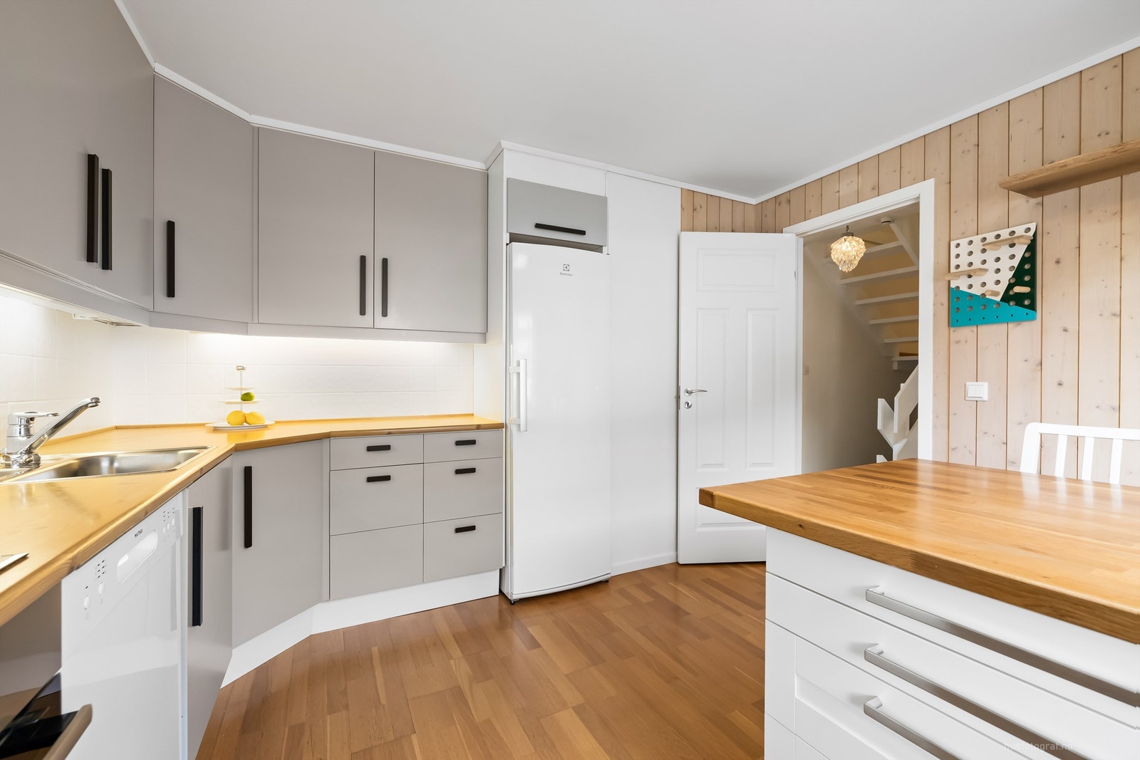 Flislagte felt over benkeplater av laminat og lysarmaturer under overskap Galleribilde