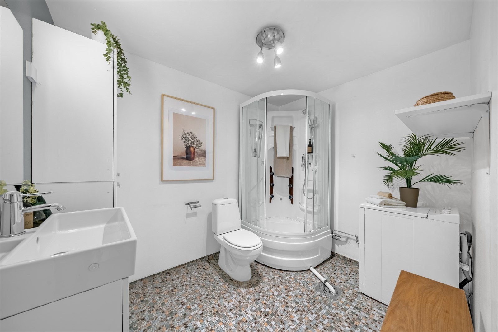 Eldre, men funksjonelt bad med servant, høyskap, wc, dusjkabinett og opplegg for vaskemaskin. Galleribilde