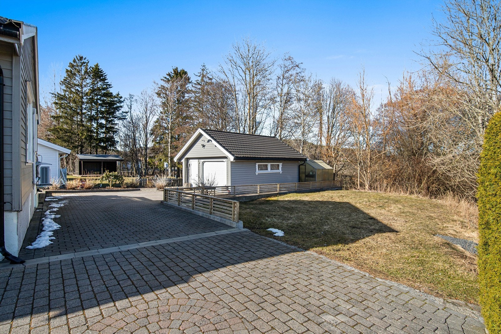 Det er rikelig med parkering både i stor hellelagt gårdsplass og egen garasje. Deler av tomten disponeres i fellesskap med naboen. Galleribilde