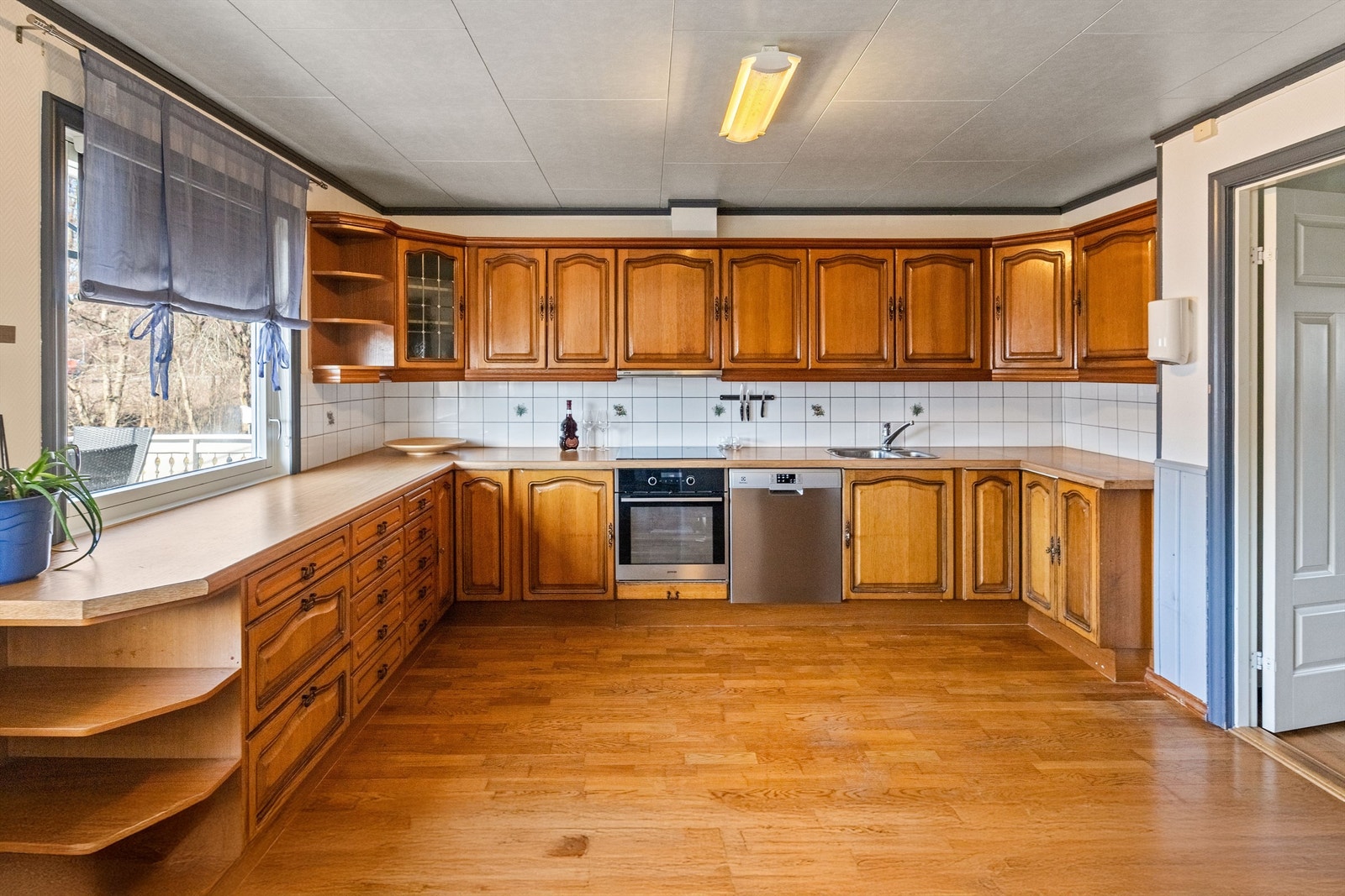 Kjøkken har innredning med profilerte fronter og benkeplater av laminat. Det er fliser på vegg mellom benkeplate og overskap. Kjøkkenet er godt utnyttet og har rikelig med både skap - og benkeplass. Galleribilde