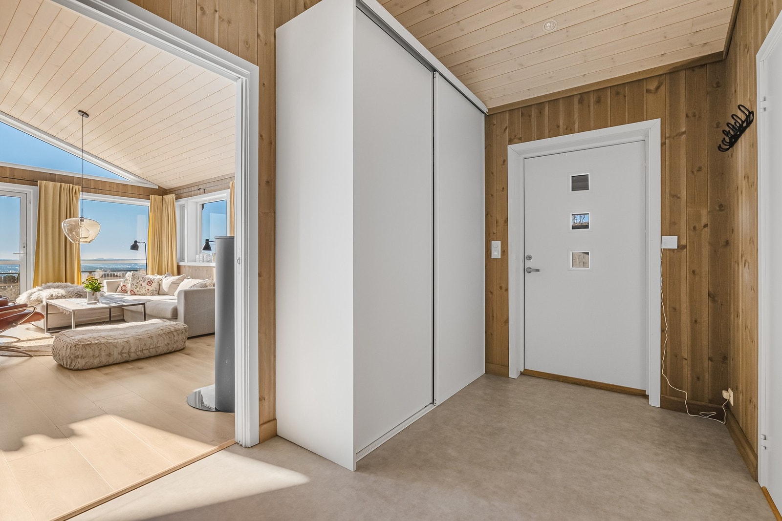 Lys og romslig entré med skyvedør inn til stue. Store vinduer gir naturlig lysinnslipp og flott utsikt. Galleribilde