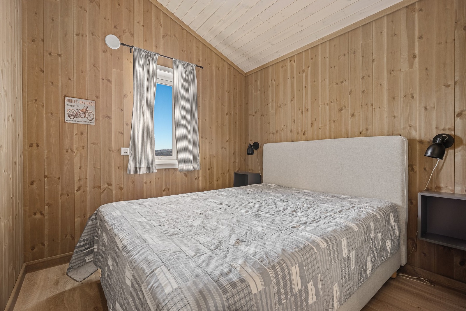 Lyst soverom med panelvegger og skråtak, vindu som gir naturlig lys. Galleribilde