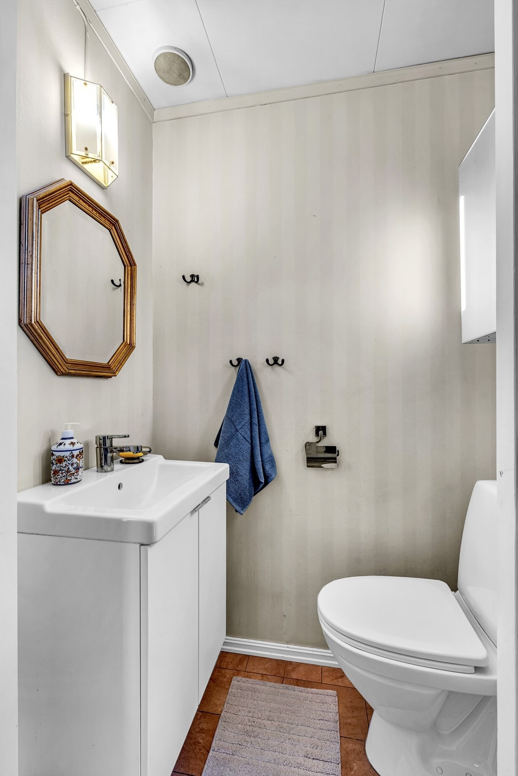 Toalettrom med fliser, vegghengt servantskap, speil og toalett - perfekt for gjester eller når du er på vei ut døren. Galleribilde