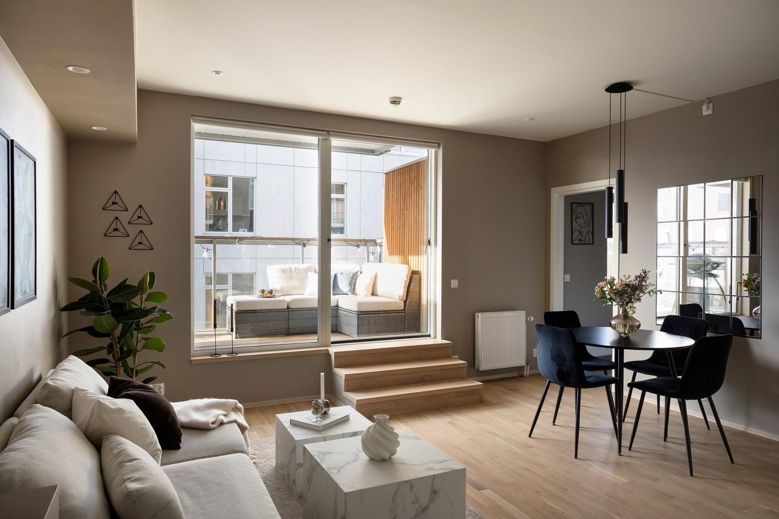 Leilighetens stue har et stilrent og moderne preg, med delikate overflater og flott parkett på gulvet. En kul detalj er trappen som fører opp mot balkongen - denne gir leiligheten penthouse-følelsen og er også fin som et sittemøbel de dagene man har gjest Galleribilde