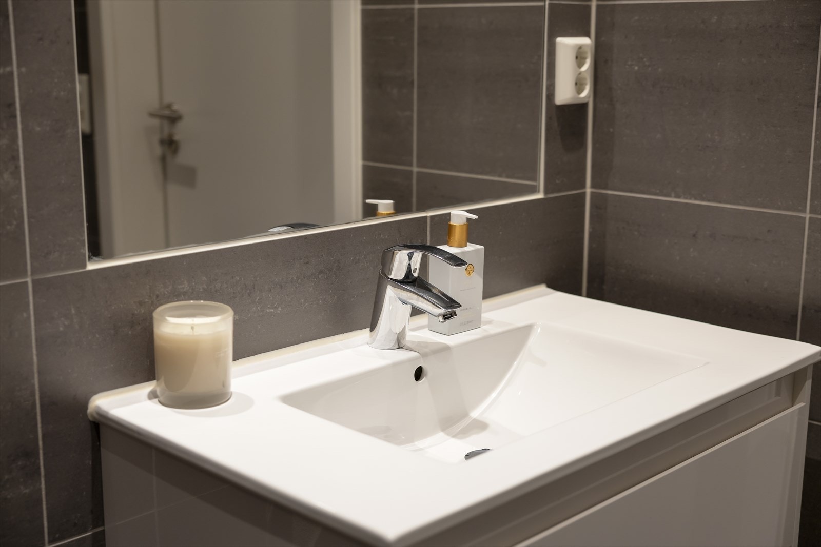 Innredningen inkluderer en heldekkende servant nedfelt i skuffeseksjon, speil med belysning, vegghengt toalett og dusj med innfellbare dusjvegger i herdet glass. Galleribilde