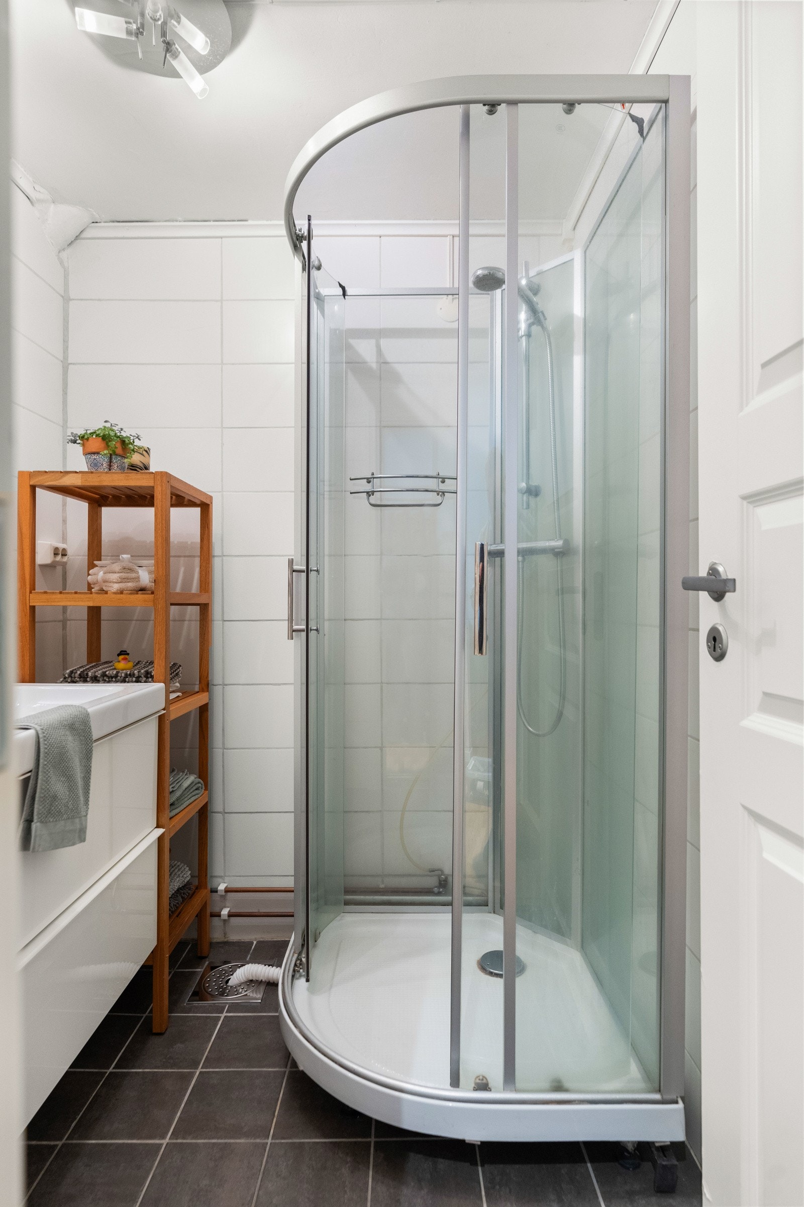 Badet består av gulvstående toalett, servant, dusjkabinett og opplegg for vaskemaskin. Galleribilde