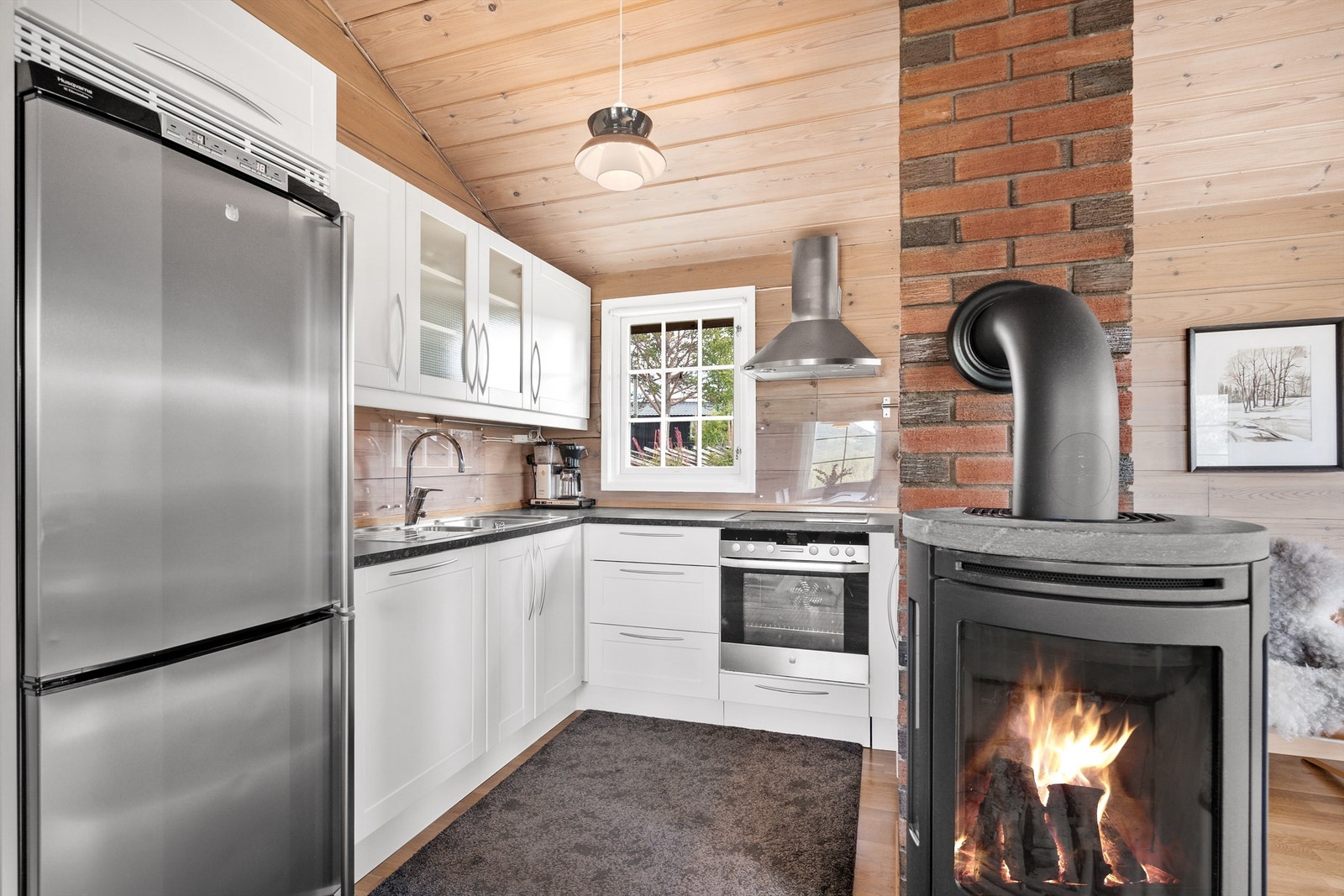 Praktisk kjøkkeninnredning. Peisovn med kleberstein, for varme og kosen. Sees fra stue og spiseplass. Galleribilde