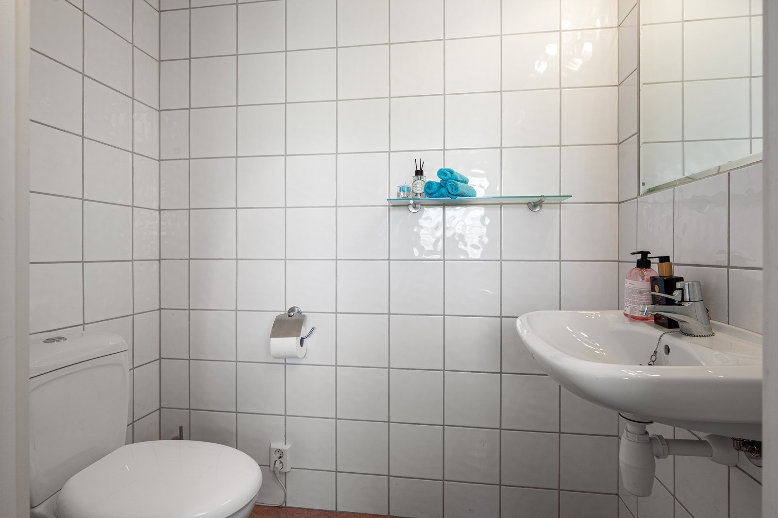 Praktisk toalettrom med fliselagt overflater. Rommet er innredet med wc og servant. Galleribilde