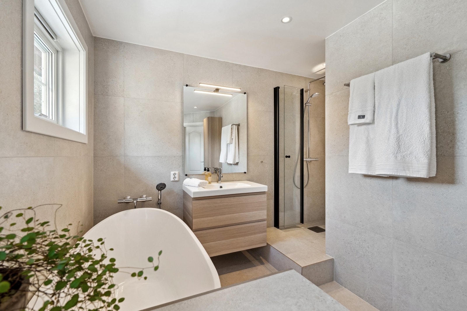 Badet er utstyrt med vegghengt toalett, badekar, og innfelbar dusjdør. Galleribilde