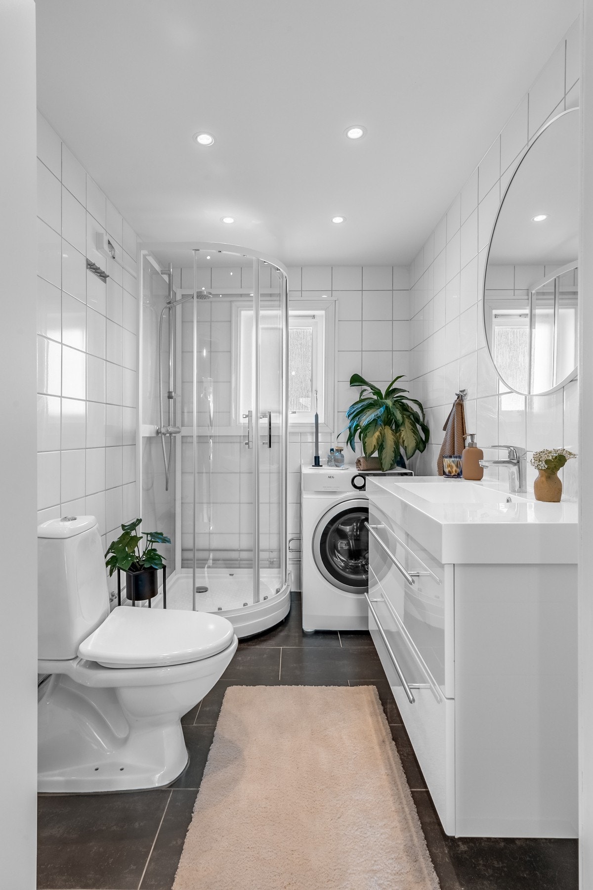 Badet er romslig med lyse, delikate veggfliser i kombinasjon med mørke gulvfliser. Galleribilde