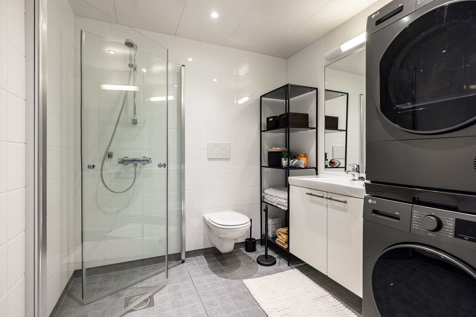 Baderommet fremstår som moderne, med innfelte downlights som gir behagelig belysning og gulvet har fliser med elektrisk gulvvarme for ekstra komfort. Galleribilde