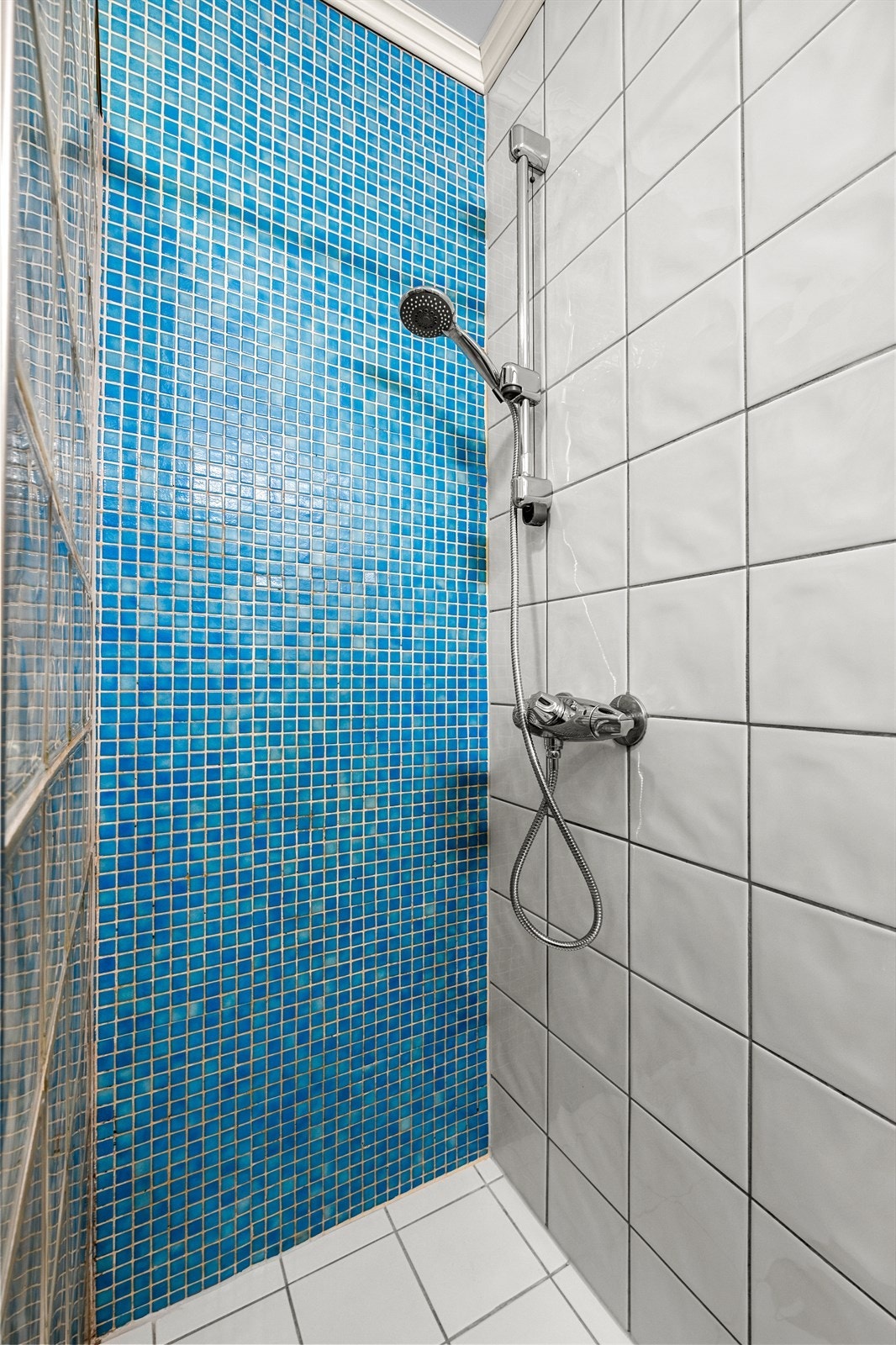 Badet byr på servant, dusjhjørne med forheng og gulvmontert toalett. Galleribilde