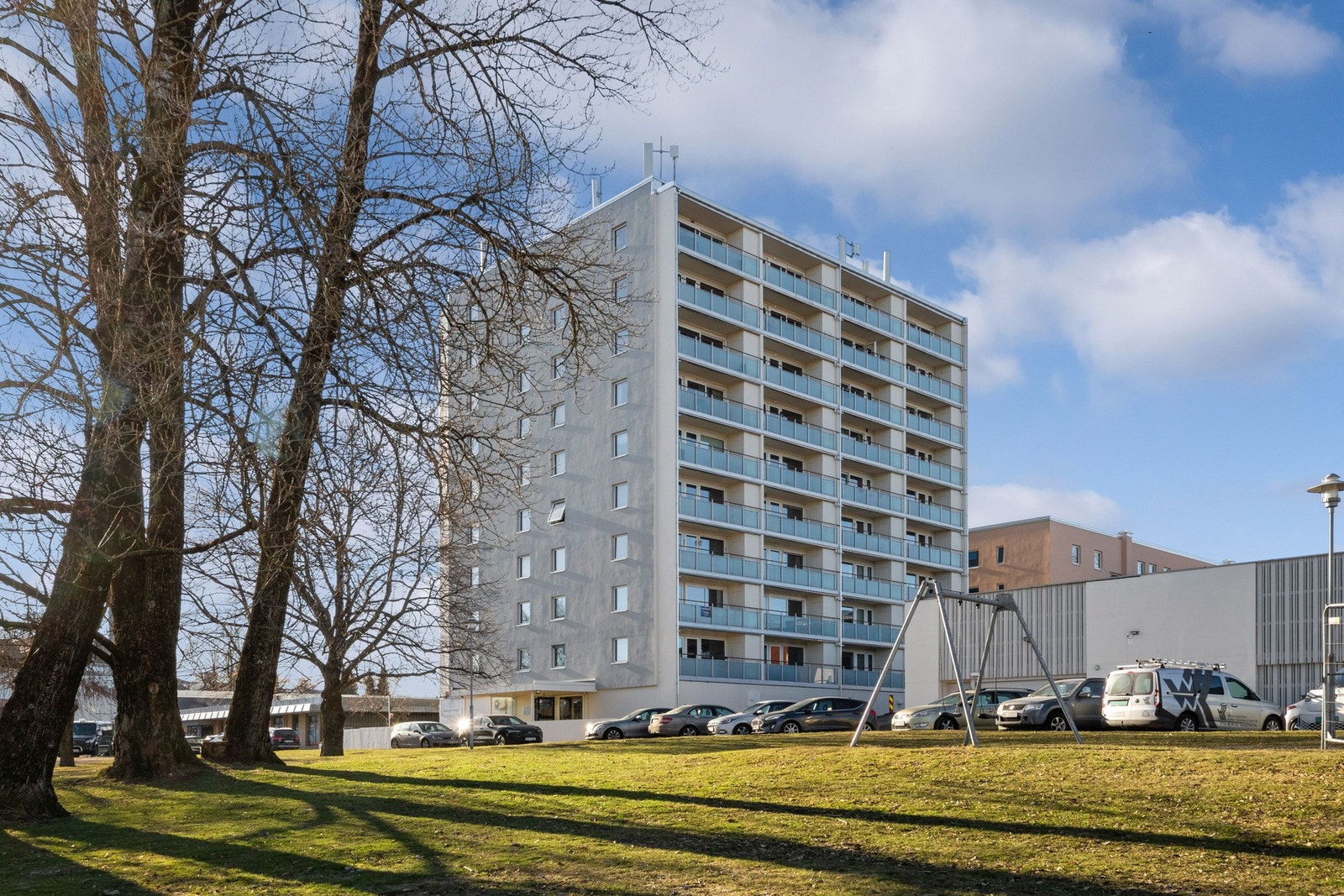 Fellesområdet rundt blokken er opparbeidet med grøntarealer, asfaltert parkering og diverse beplantning. Galleribilde