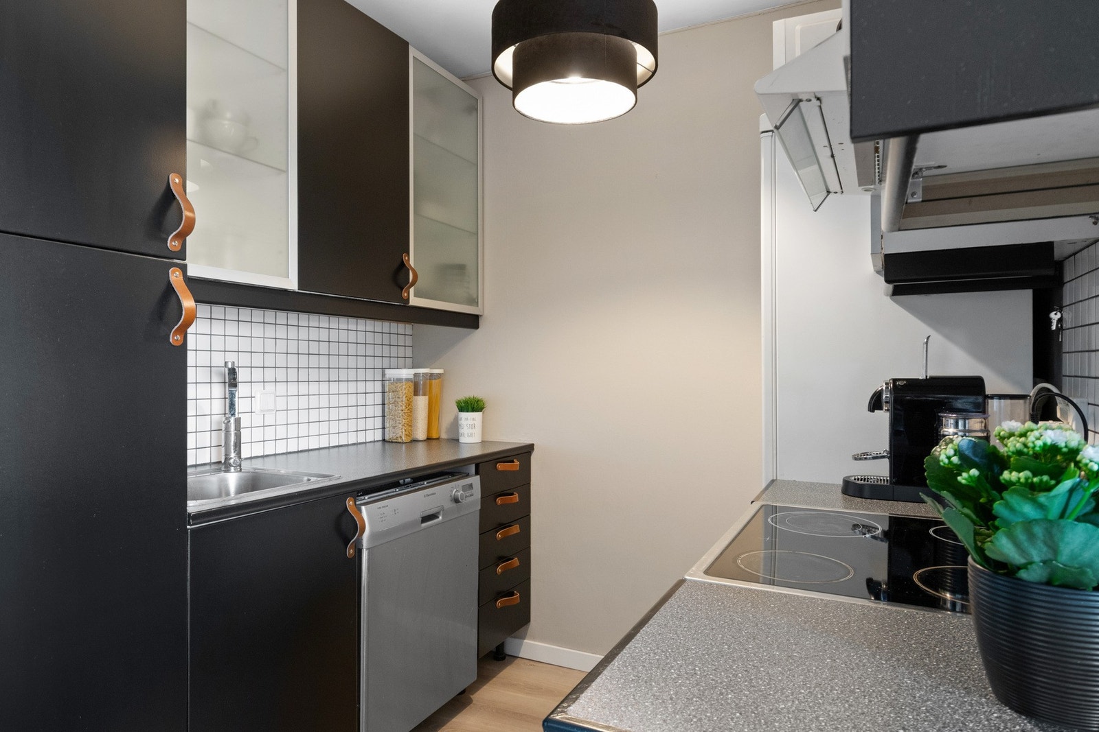 Innredningen har sorte, glatte fronter, frostede vitrineskap, praktisk høyskap og grå benkeplate av laminat. Galleribilde