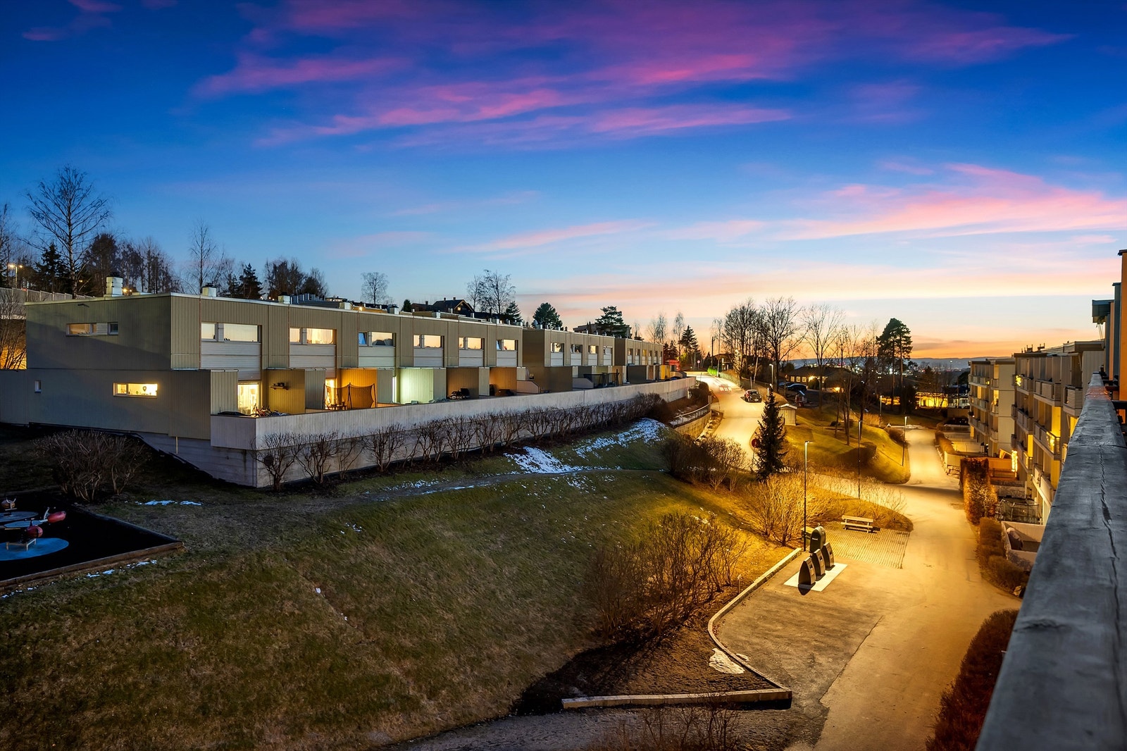 Utsikten fra balkongen, kveldstid.
Her finner du gjesteparkering og nedkjøring til egen disponible garasjeplass med elbil-lader. Galleribilde
