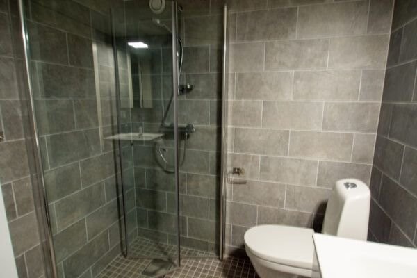 På badet er det dusjdører i glass som kan dyttes inn og gjør at badet oppleves romslig Galleribilde