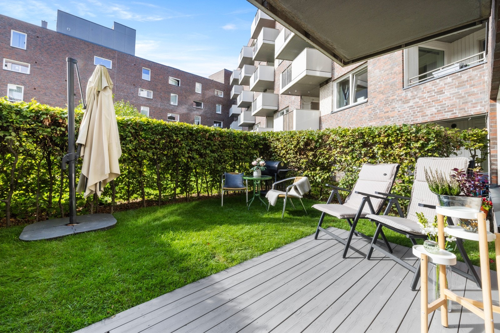 Fra terrassen er det adkomst til en lettstelt hageflekk med plen som er godt skjermet med høye hekker Galleribilde