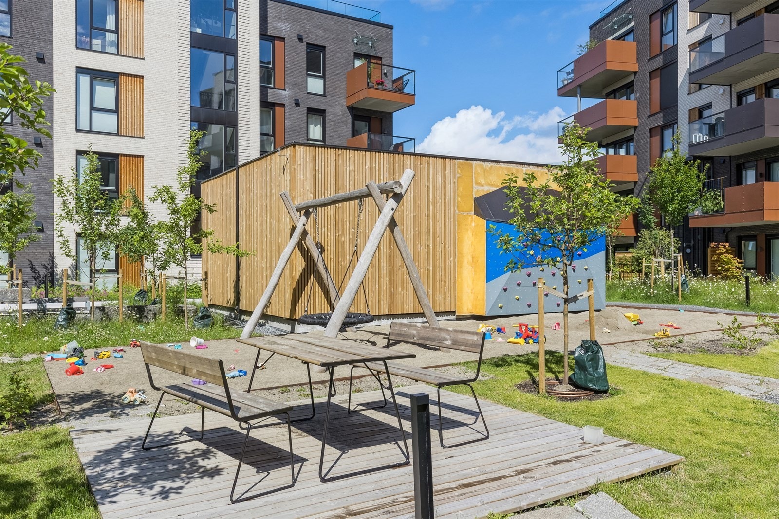 Gårdsrommet er grønt og harmonisk med flott beplantning, vannrenne, sitteplasser, sandkasse, klatrevegg og sykkelpaviljong. Galleribilde