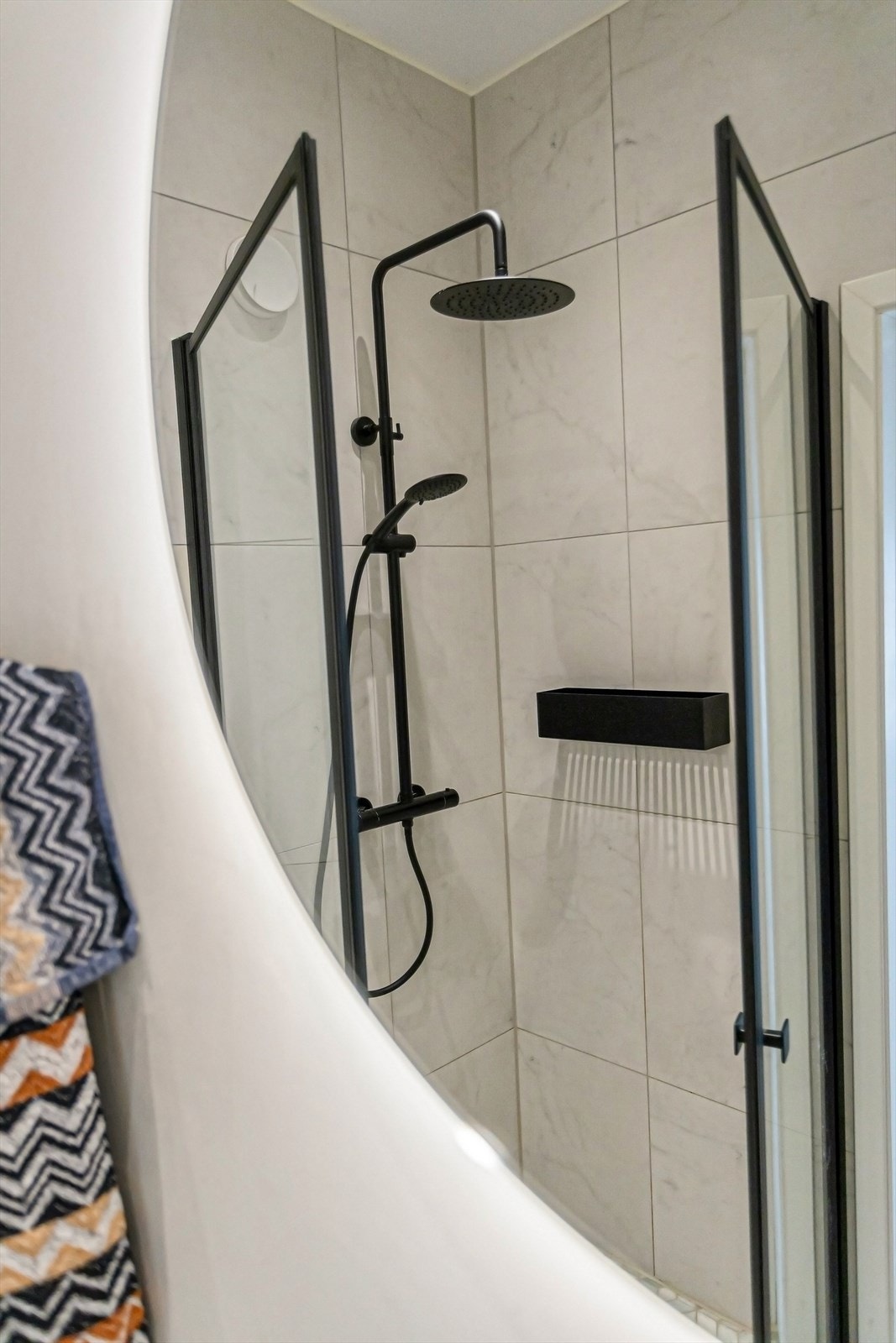 Rommet er utstyrt med dusjhjørne med innfellbare glassdører, blandebatteri, regndusj og håndholdt dusj, veggmontert toalett og baderomsinnredning med servant skap, servant og blandebatteri fra Gustavsberg. Galleribilde