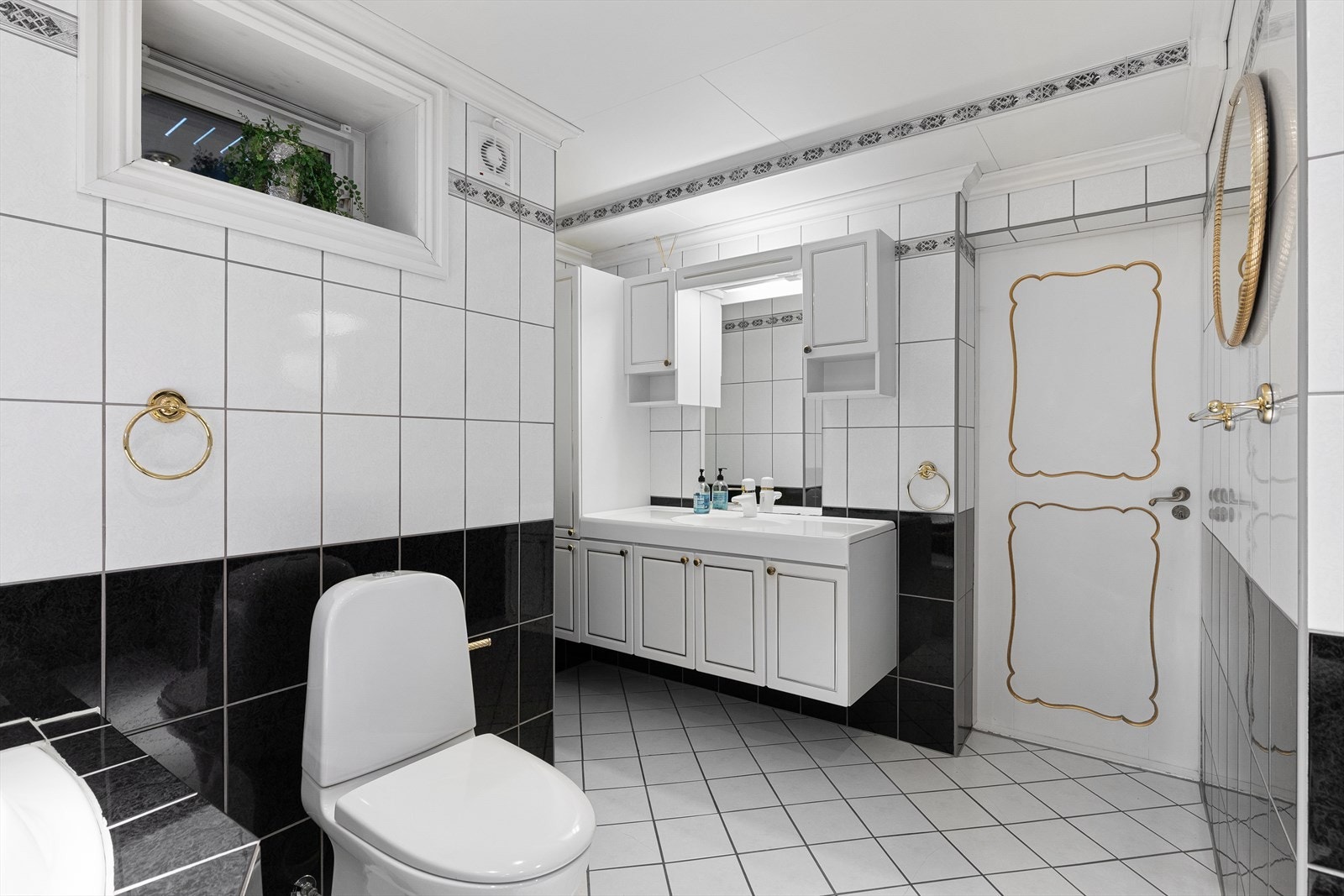 Inneholder innfliset badekar og speil, servant med skaper, toalett og opplegg for vaskemaskin. Galleribilde