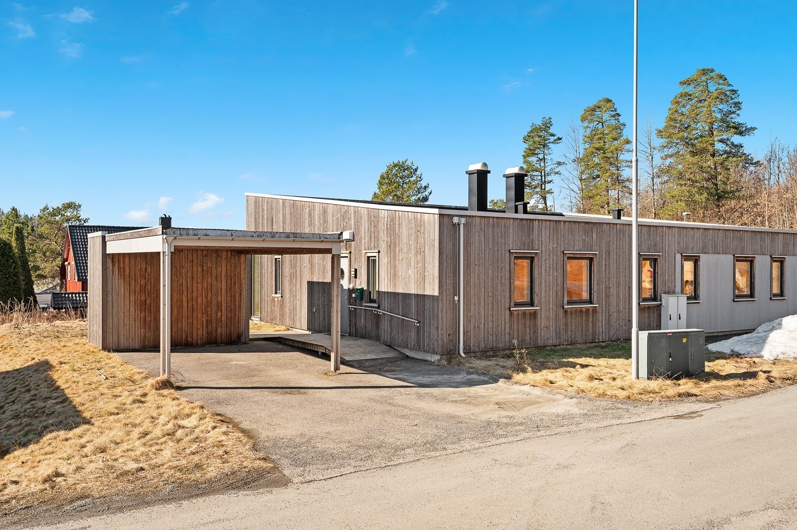 Fasade med inngangspartiet og carport. God sportsbod i bakkant av carporten. Asfaltert innkjørsel. Galleribilde