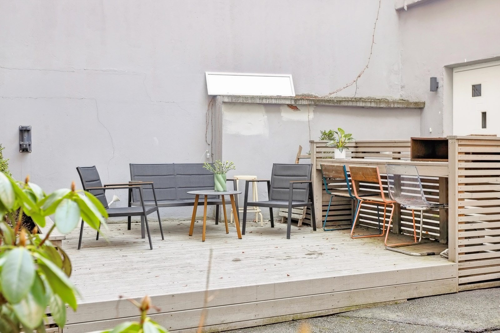Lukket bakgård med terrasseplatting hvor det er plassert stoler og bord, samt benker Galleribilde