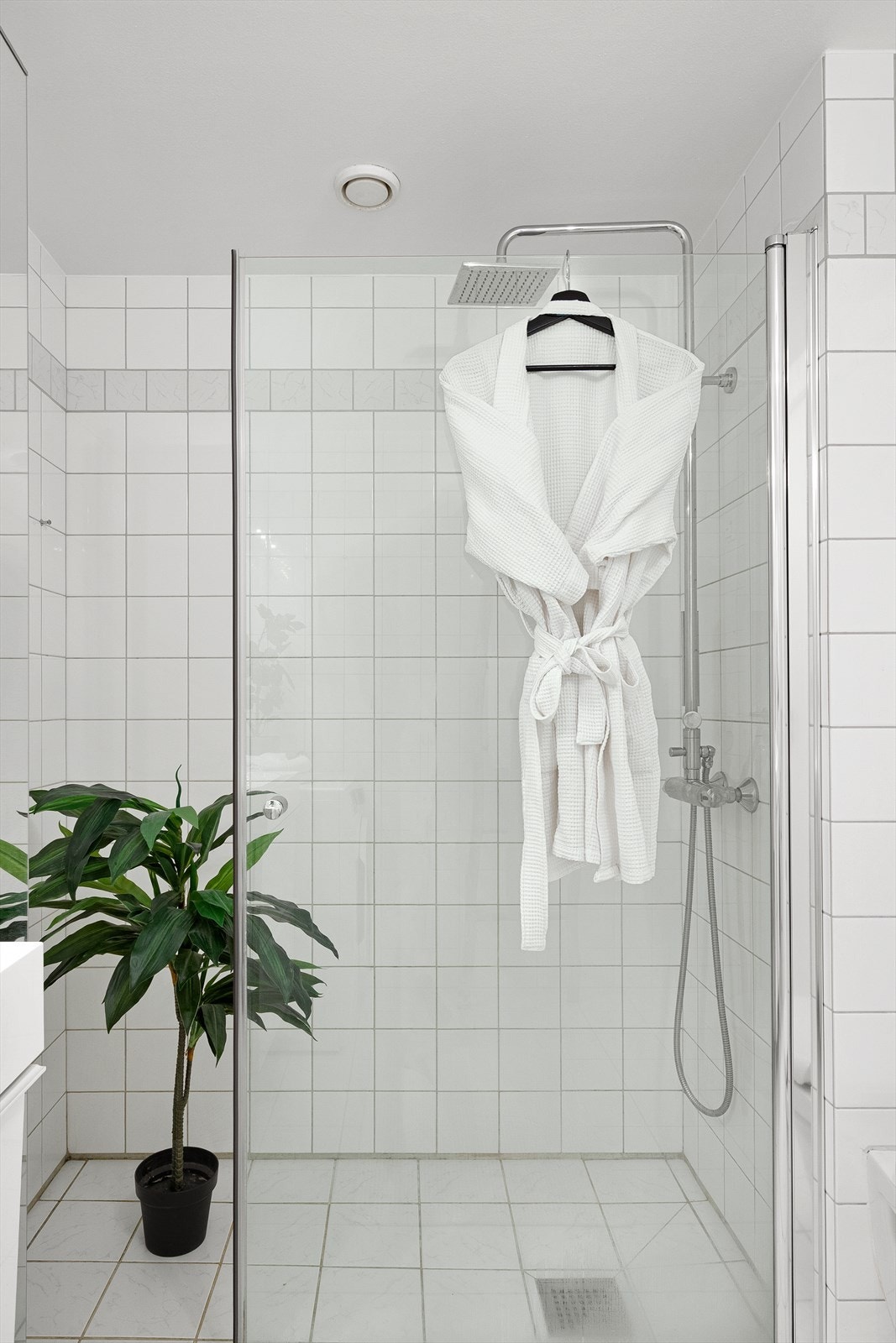 Badet er bl.a. utstyrt med innfellbare dusjdører, opplegg for vaskemaskin, servantskap og veggmontert wc Galleribilde