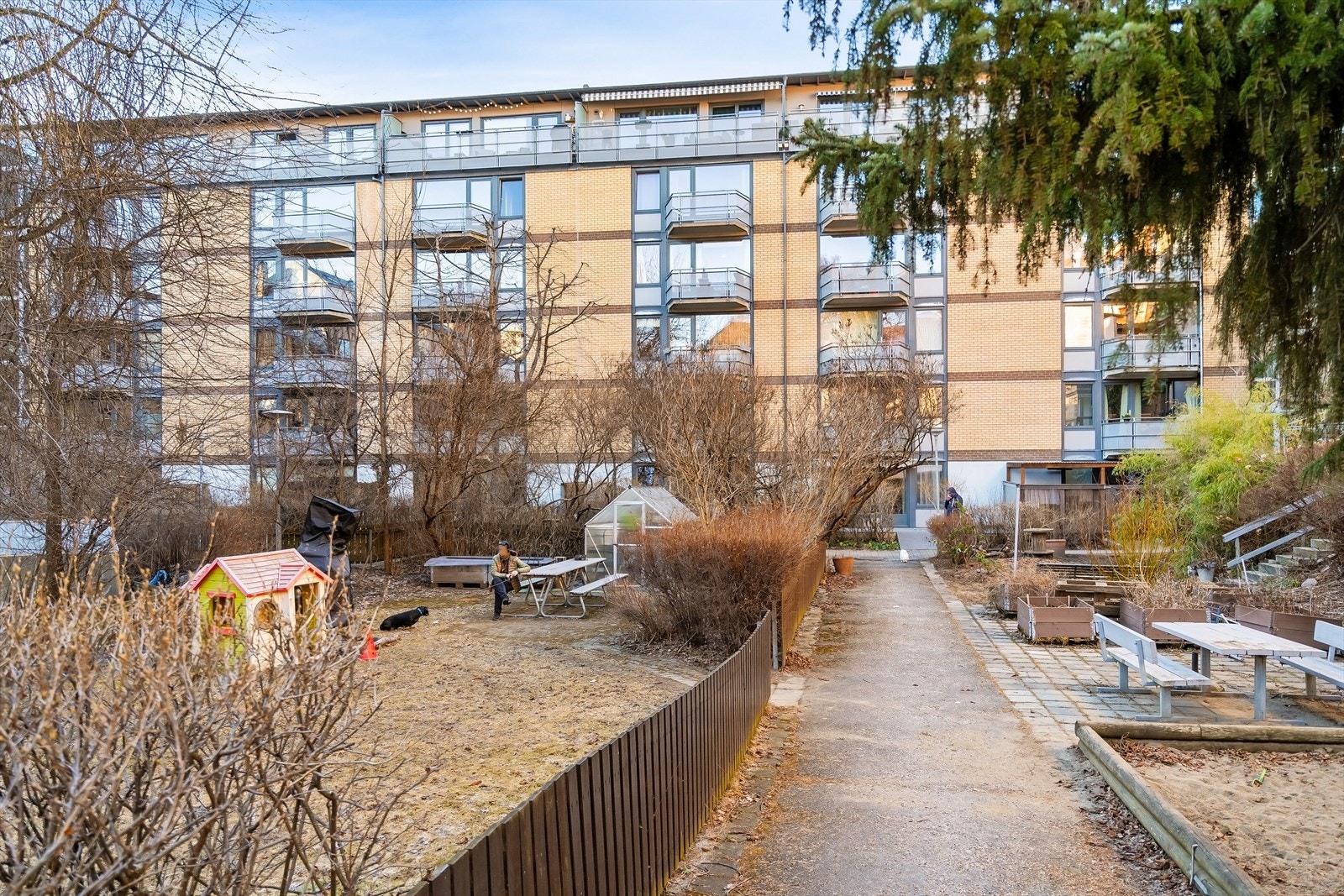 Hyggelig bakgård med lekeplass, benker, drivhus og beplantning Galleribilde