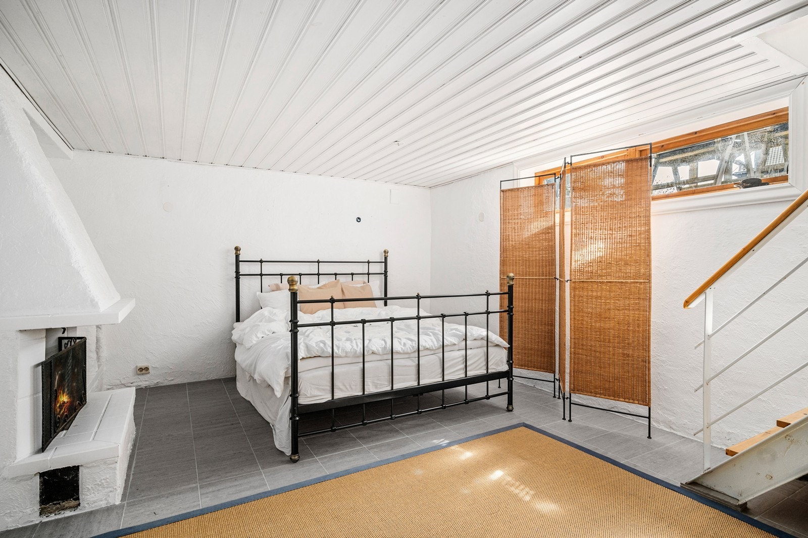 Kjellerstue i underetasjen med åpen peis. Benyttet som gjesterom. Galleribilde