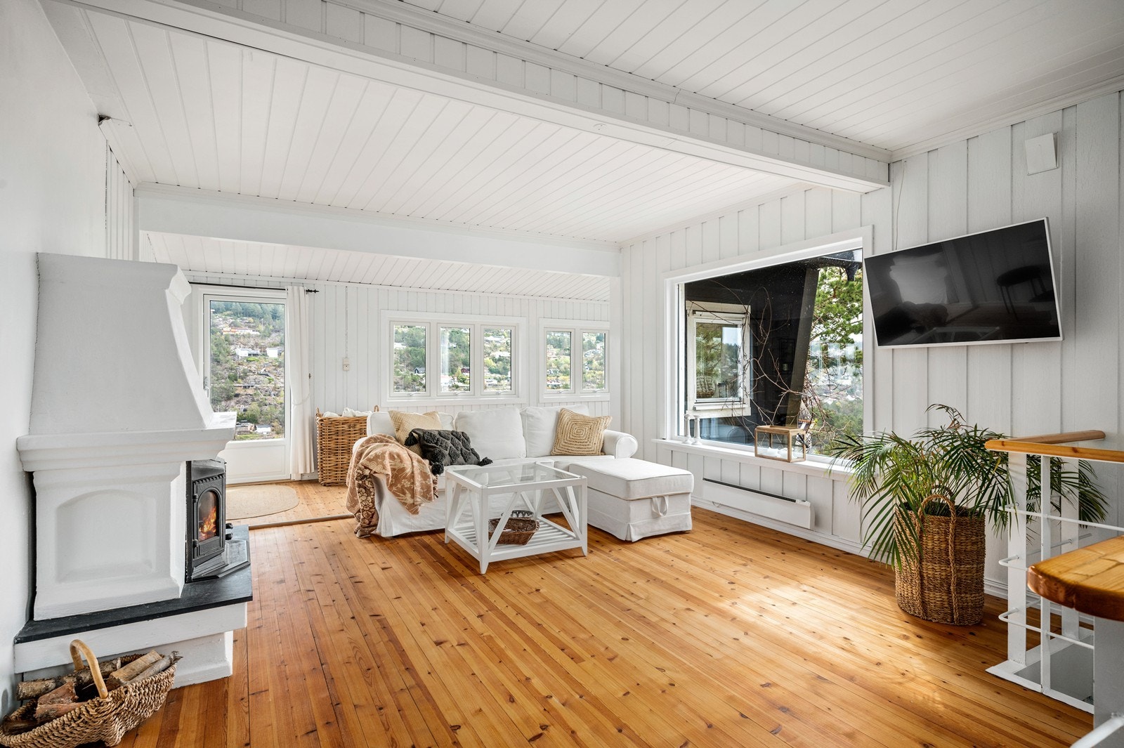 Stor og lys stue med heltre gulv og peis med innsats. Galleribilde