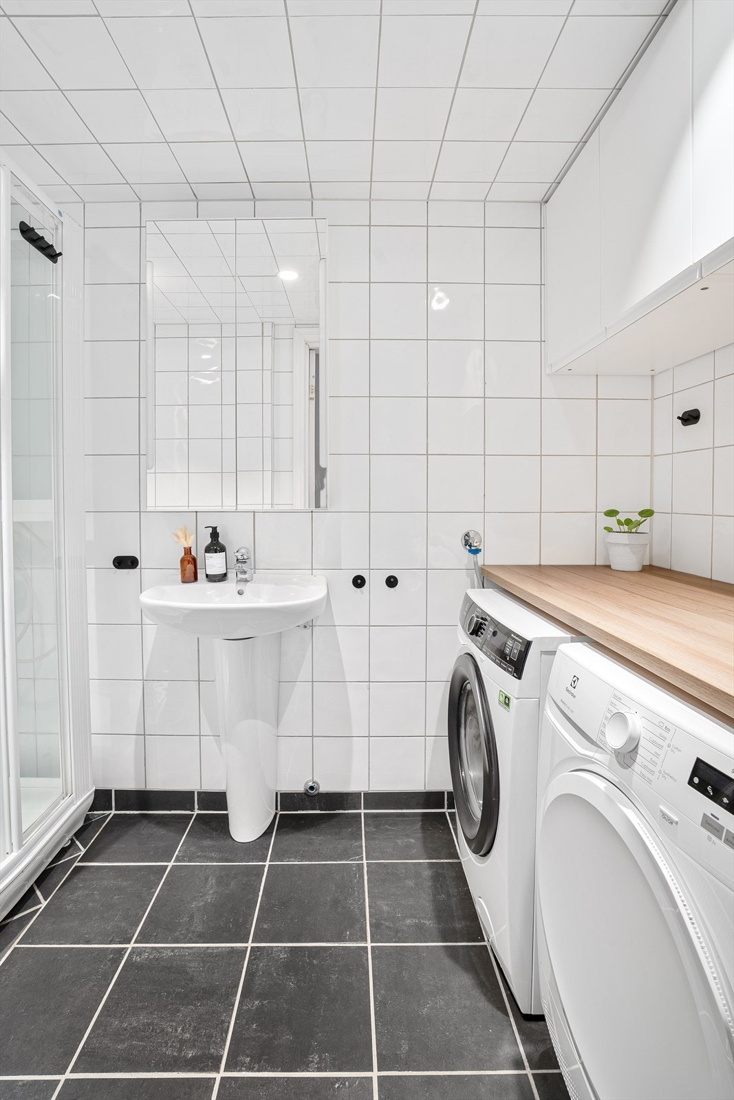 Badet har vegghengt servant med ettgreps armatur, speilskap med belysning på vegg over servant, gulvstående toalett, benkeplate av laminat og vegghengte skap over benkeplate. Galleribilde
