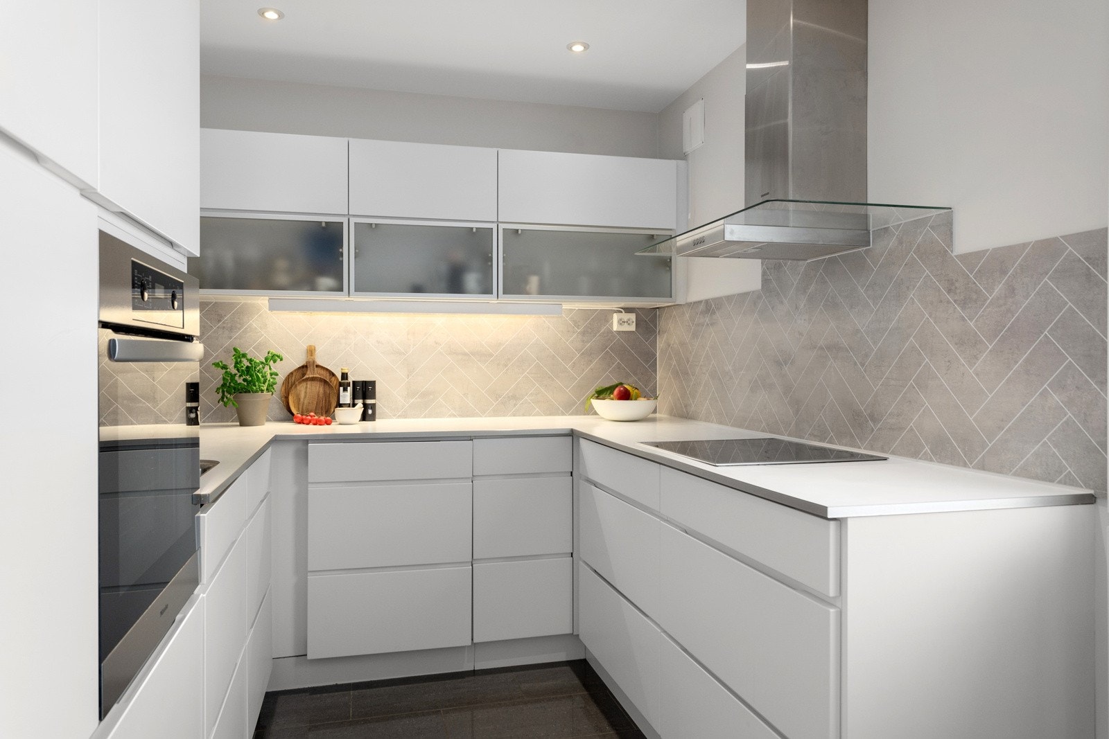 Kjøkkeninnredning fra 2010-11 med hvite glatte fronter, overskap med frostet glass, integrerte håndtak/grep og hvite laminerte benkeplater. Opplegg og plass for vaskmaskin Galleribilde